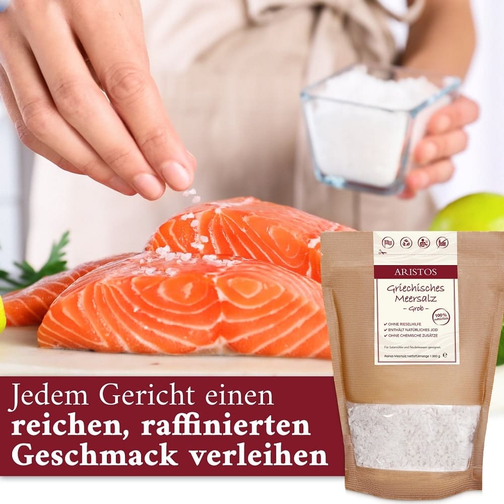 Hand salzt rohe Lachsfilets, rechts daneben steht der Beutel ARISTOS Griechisches Meersalz