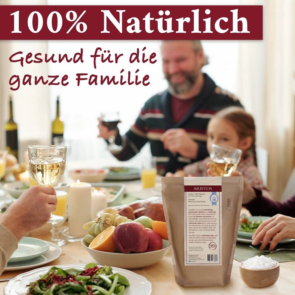 Familie stößt an einem gedeckten Tisch an, davor die Rückseite des ARISTOS-Meersalzbeutels