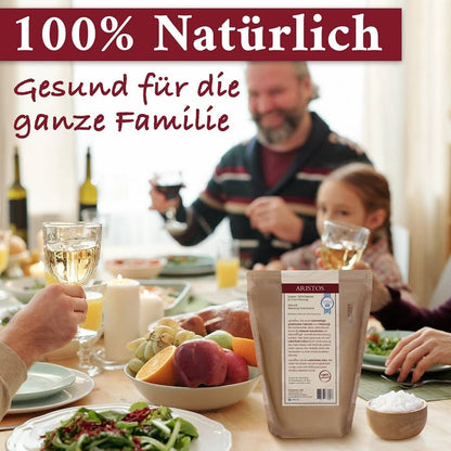 Familie stößt an einem gedeckten Tisch an, davor die Rückseite des ARISTOS-Meersalzbeutels